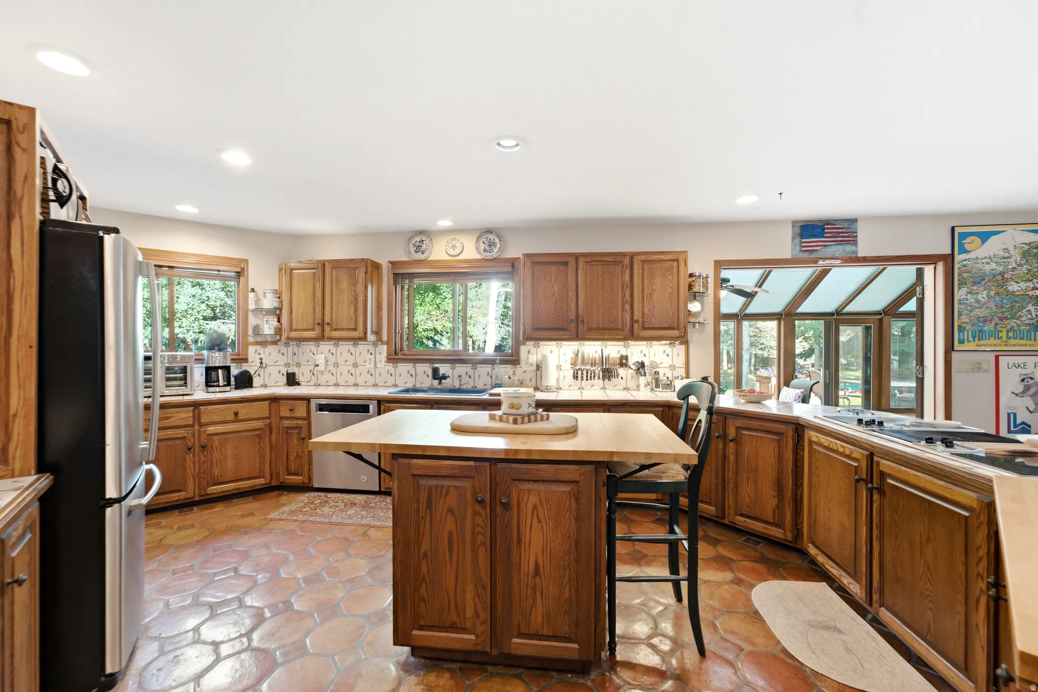 Kitchen featuring wood cabinetry, stainless steel appliances, a center island with seating, and terracotta tile flooring