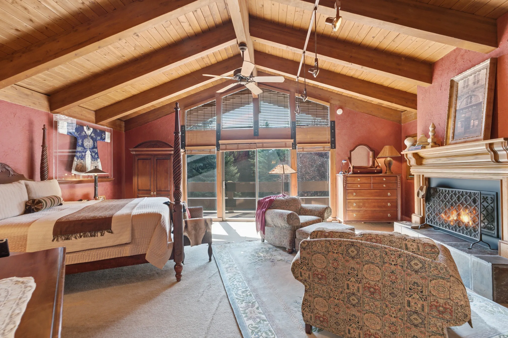Primary with vaulted wood-paneled ceiling with exposed beams, full-height glass windows, and a built-in fireplace with a decorative mantel
