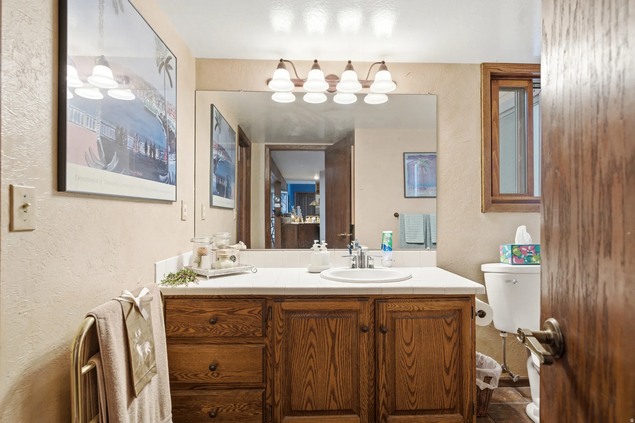 Warm wood-finish vanity with ample storage drawers and cabinet, integrated sink, and extended countertop