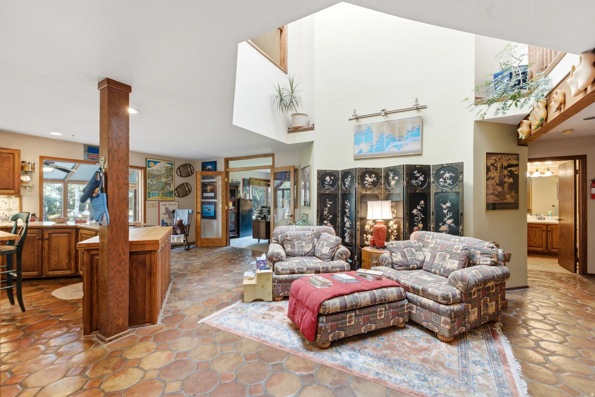 Two-story ceilings with expansive windows, wood-finish kitchen cabinetry, and hexagon tile flooring