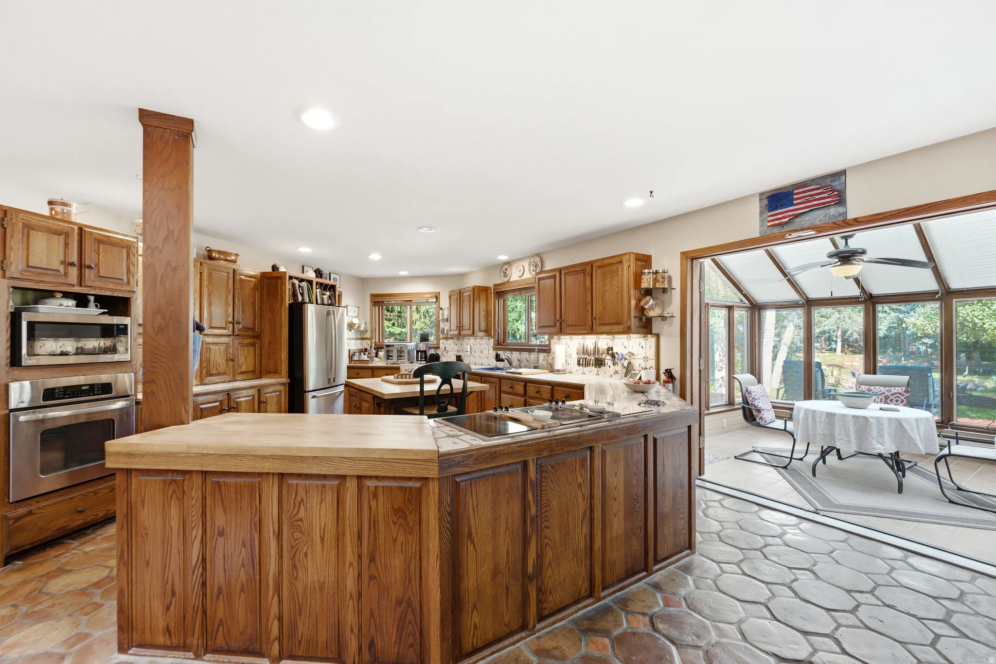 Spacious kitchen with wood cabinetry, integrated stainless steel appliances, and a central island