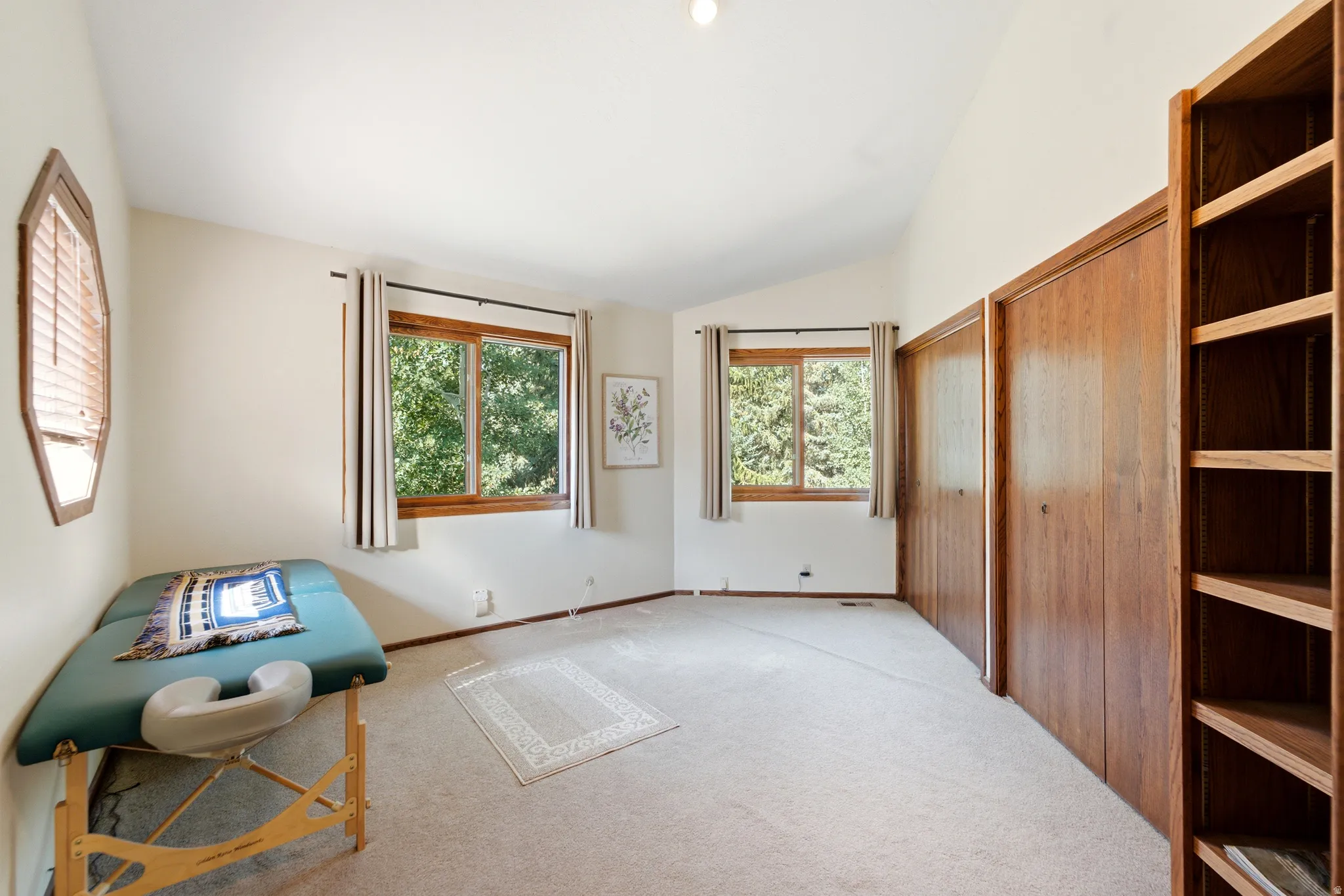 Bedroom 2 - Vaulted ceilings, a built-in wood bookshelf, wood-framed windows, and carpeted flooring