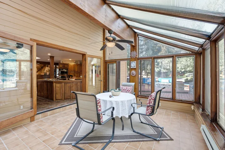 Sunroom featuring a full-length glass ceiling, wood-framed windows, and tile flooring