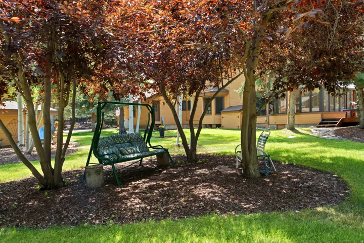 Expansive green lawn with mature trees and dark mulch ground cover