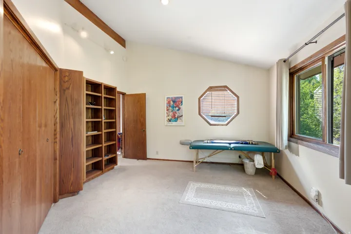 Bedroom 2 - Vaulted ceiling, exposed wood beams, octagonal window, full-height built-in shelving, track lighting