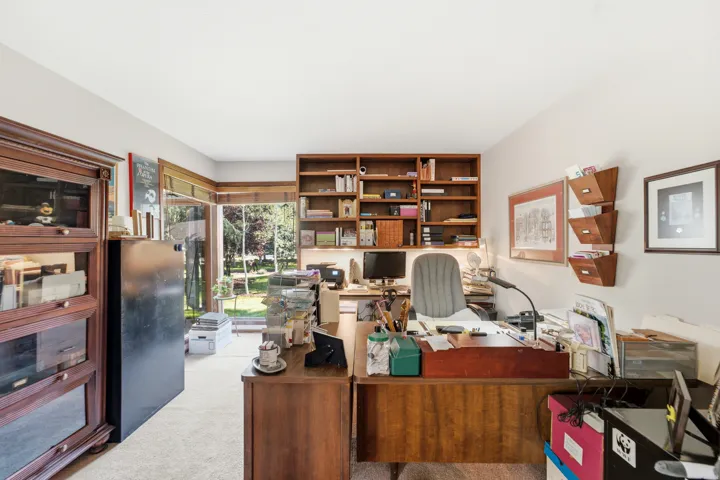 Built-in wood shelving, wood-finish desk, and large picture windows