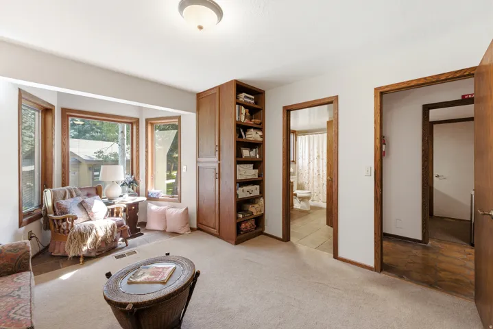 Recessed bay window, built-in shelving, wood-finish trim, ceiling-mounted light fixture, and neutral carpet