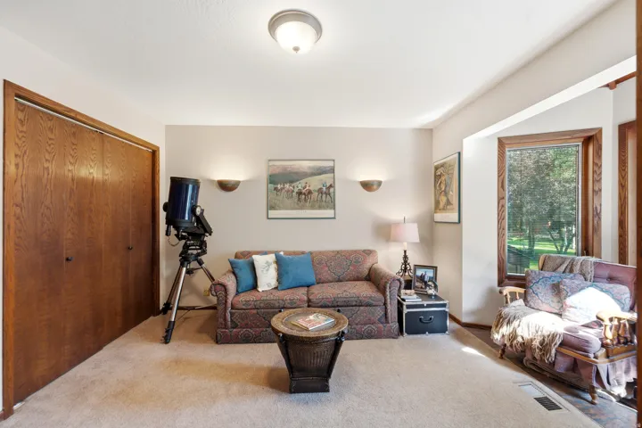 Built-in closet with wood-finish doors, bay window with wood trim, wall-mounted sconces, and overhead flush-mount lighting