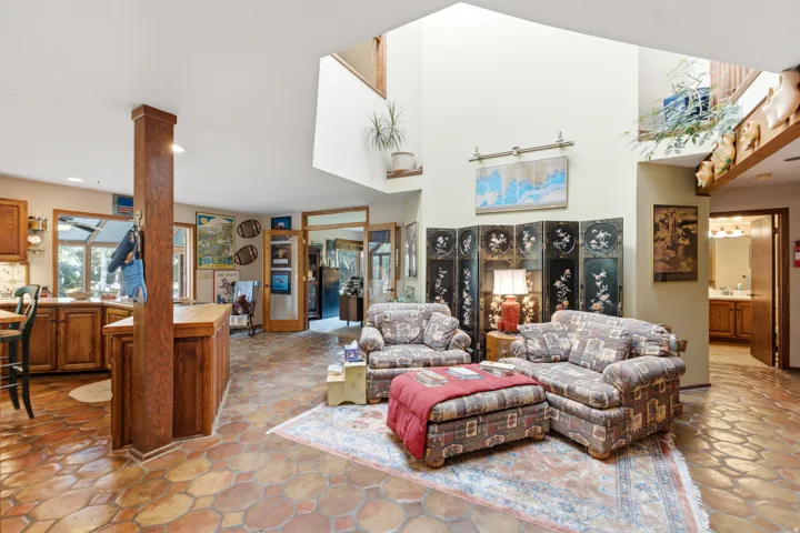 Two-story ceilings with expansive windows, wood-finish kitchen cabinetry, and hexagon tile flooring