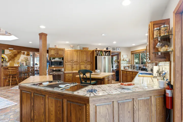 Spacious kitchen featuring extensive wood cabinetry, tile countertops, a built-in oven, and a large central island
