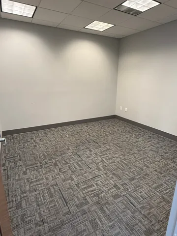 Recessed ceiling lighting, light gray painted walls, dark gray baseboard trim, and patterned carpet flooring