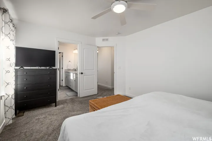 White walls, gray carpet flooring, and a ceiling fan with integrated lighting