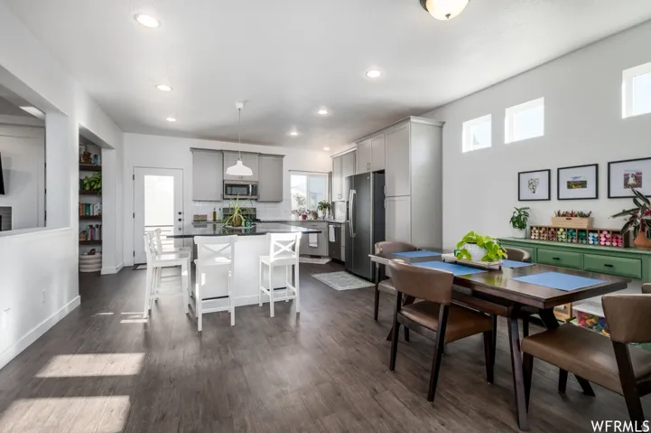 Open-concept kitchen and dining area featuring wood-finish flooring, recessed lighting, light gray cabinetry, and a kitchen island with seating