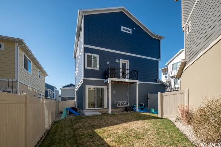 Expansive backyard featuring a privacy fence, a ground-level patio, and a second-story balcony with metal railing