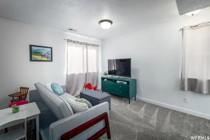 White walls, recessed lighting, and a window with curtain rod