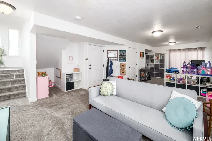Carpeted flooring throughout, recessed lighting fixtures, white painted walls, and a white interior door with black hardware