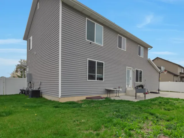 Gray siding exterior with multiple windows, a rear entry door, and a concrete patio