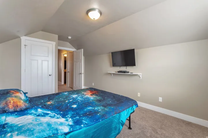Spacious upper-level bedroom featuring vaulted ceilings, recessed lighting, and neutral wall finishes