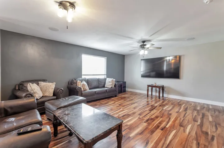 Spacious room featuring wood-finish flooring, a ceiling fan, and recessed lighting