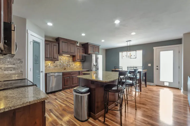 Gourmet kitchen featuring rich wood cabinetry, granite countertops, stainless steel appliances, and pendant lighting over a center island