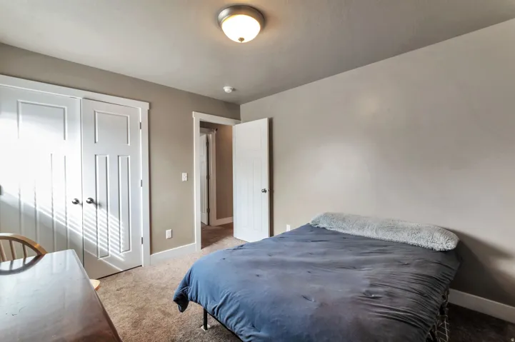 Spacious bedroom featuring neutral wall finishes, a ceiling-mounted light fixture, and direct access to a walk-in closet