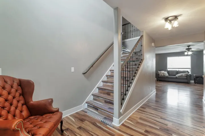Open-concept living featuring a curved staircase with metal railings and wood-finish treads, hardwood flooring throughout the main level, and abundant natural light from large windows