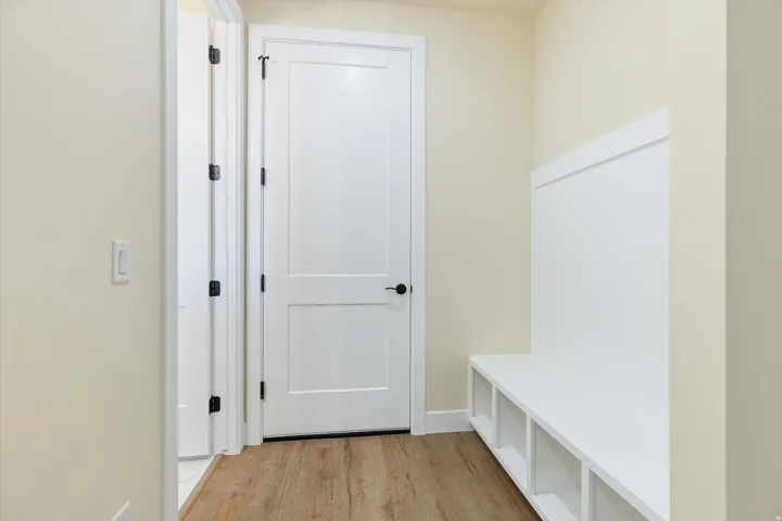 Built-in bench with cubby storage and beadboard paneling, wood-finish flooring, two-panel interior doors, and black hardware