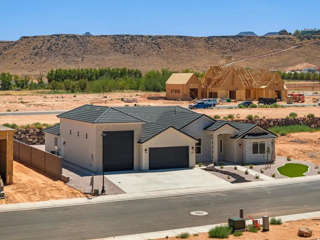 Modern residence featuring a clean-lined architectural design with stucco exterior, dark metal roof, and multiple garage bays