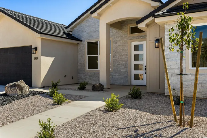 Modern exterior featuring stone veneer accents, a tiled roof, and a contemporary entry door with frosted glass panels
