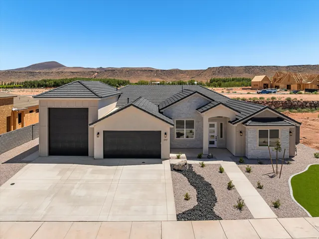 Modern residence showcasing a clean-lined architectural design with a stucco exterior, metal roof with geometric peak detailing, and a three-car garage configuration
