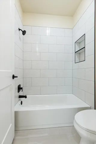 Clean and bright bathroom featuring white subway tile walls, a soaking tub with integrated shower, matte black fixtures and hardware, a recessed medicine cabinet, and light-finished flooring