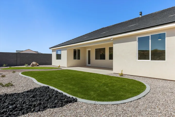 Modern residence with a curved lawn featuring lush green turf, complemented by gravel hardscaping and decorative black stone accents