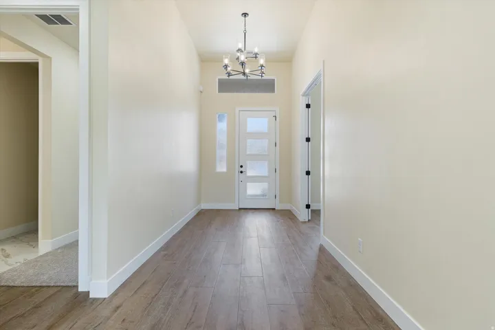 Wood-finish flooring, contemporary chandelier, transom window, frosted glass sidelight, and multi-pane front door
