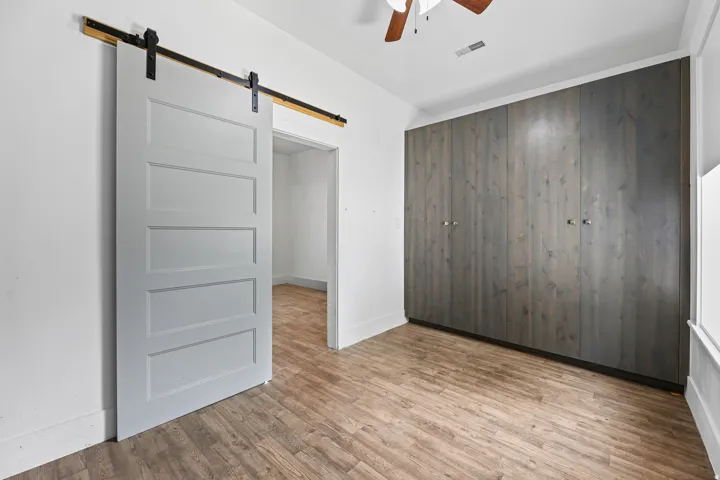 Wood-finish flooring, white walls, and a wood-toned ceiling fan