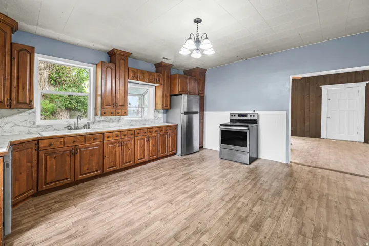 Kitchen featuring extensive wood cabinetry, wood-finish flooring, a stainless steel electric range, and a stainless steel refrigerator