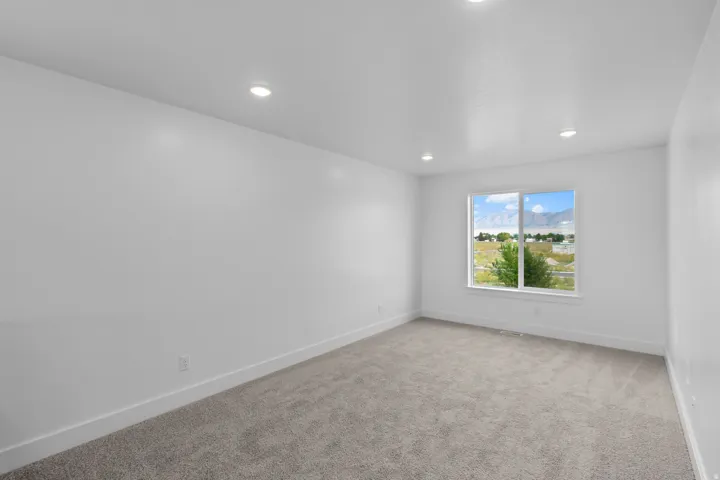 Recessed ceiling lighting, white painted walls, window with mountain backdrop, and carpeted flooring