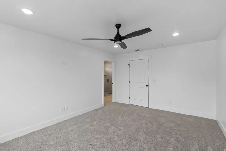 Spacious bedroom with neutral wall finishes, plush carpet flooring, and recessed ceiling lighting