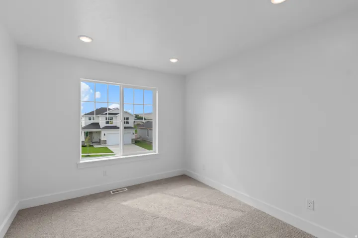 Carpeted interior space with a large window featuring muntin bars, recessed lighting, and crisp white walls