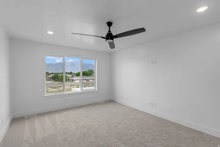 Recessed lighting, ceiling fan, carpet flooring, large window, and mountain backdrop