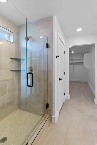 Primary bathroom suite featuring a frameless glass-enclosed walk-in shower with linear floor drain, dual built-in shelving niches, and brushed black hardware