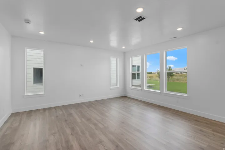 Wood-finish flooring, recessed ceiling lighting, multiple large windows, and white trim