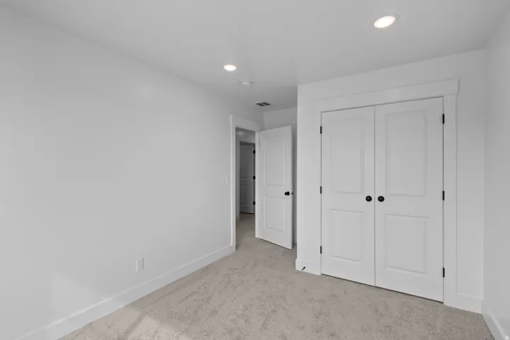 Neutral wall tones, recessed ceiling lighting, textured carpeting, and white trim