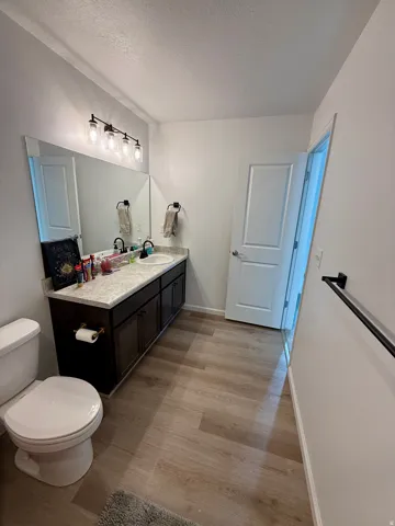 Wood-finish flooring with a dual vanity featuring dark wood cabinetry and a light-toned countertop