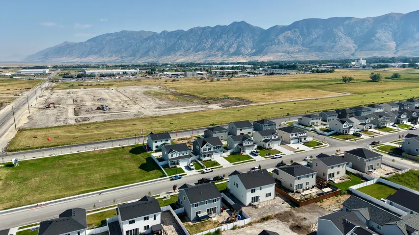 Mountain range backdrop, residential street, manicured lawns, newly constructed properties, structured community layout
