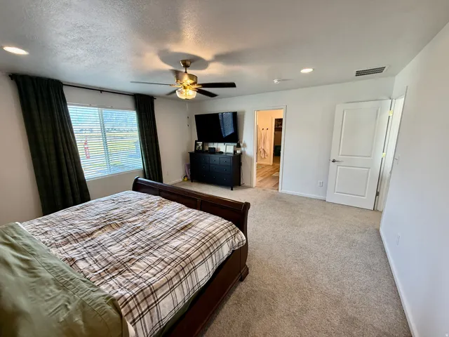 Master bedroom-Wall-to-wall carpeting with recessed lighting, a ceiling fan with integrated light, and a window with blinds
