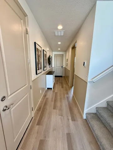 Recessed lighting illuminates the hallway featuring wood-finish flooring and a neutral two-tone wall treatment