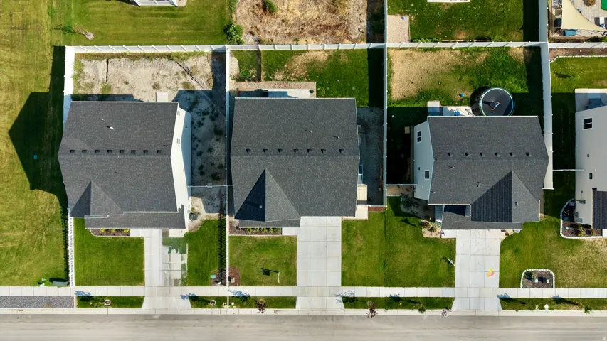 Aerial view showcasing three newly constructed homes with charcoal asphalt roofing, clean architectural lines, and manicured front lawns