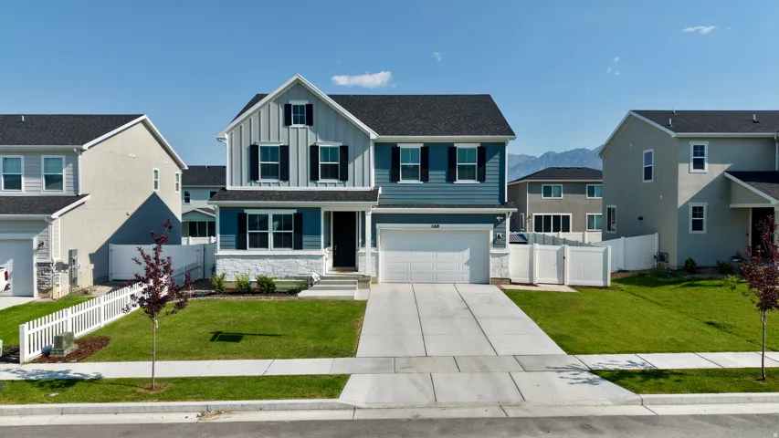 Two-story residence featuring blue siding, white stone accents, a two-car garage, and a concrete driveway