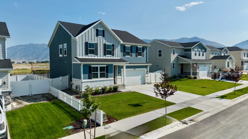 Two-story residence with a two-car garage, dark-paneled shutters, and a white picket fence