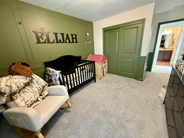 Wall paneling detail, plush carpeting, built-in closet with bifold doors, integrated storage, and access to an additional bathroom